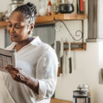 Smiling African American woman reading the newspaper in the morning